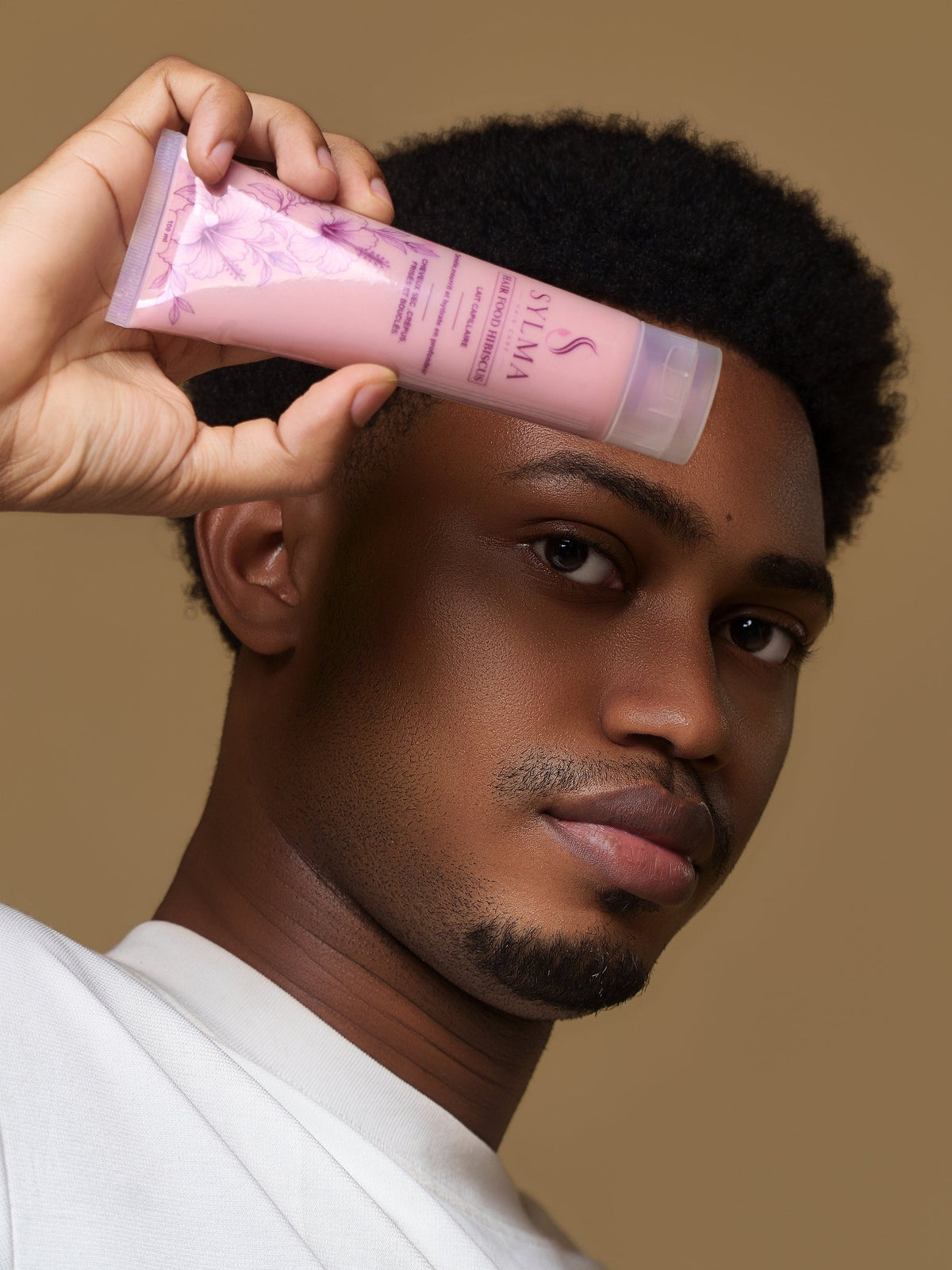 Homme tenant le lait capillaire Hair Food Hibiscus Sylma